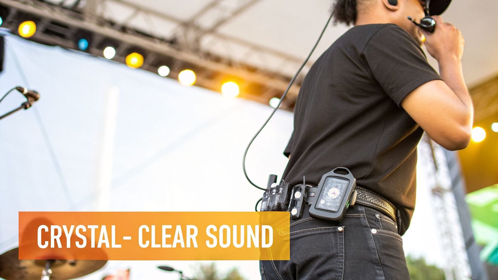 Rear view of a sound engineer wearing an in-ear monitor system and audio equipment on belt.